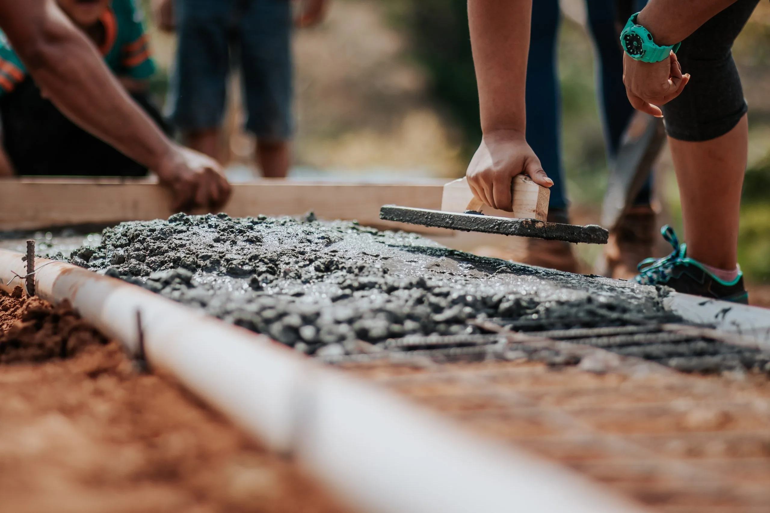 Handwerker glättet frisch gegossenen Beton auf einem Fundamentstreifen.