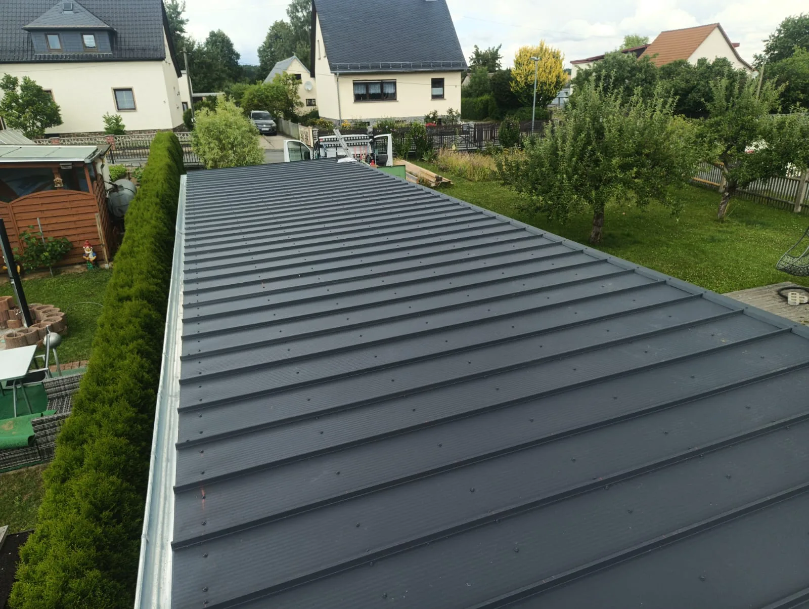 Fertig eingedecktes Flach-/Pultdach eines Holzrahmenbaus mit dunkler Stehfalz-Metalldeckung und Dachrinne.