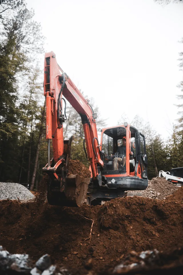Kompaktbagger arbeitet auf einer Waldparzelle im Erdbau.