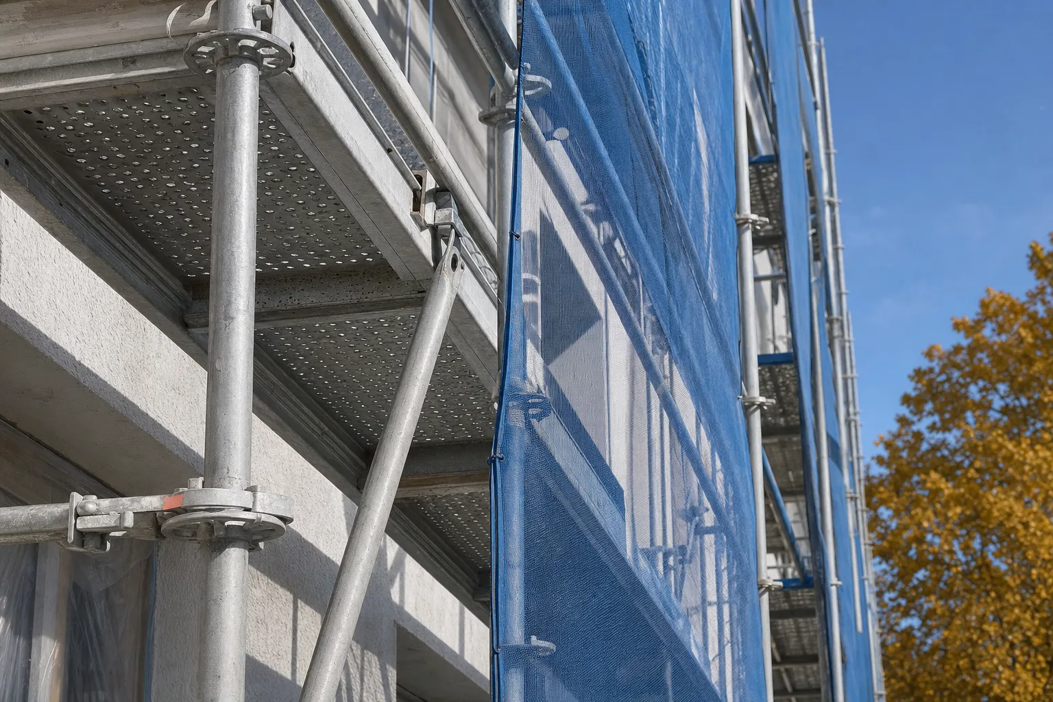 Verzinktes Gerüst mit Sicherheitsnetzen an einer sanierten Hausfassade.