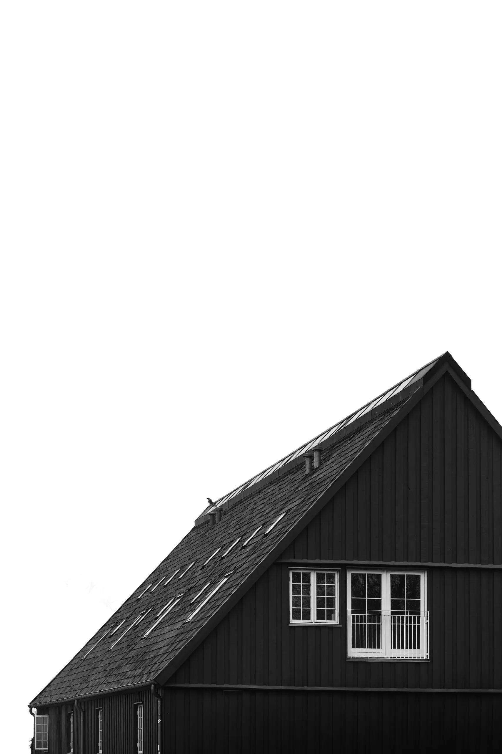 Wohnhaus mit dunkler Holzverkleidung, geneigtem Ziegeldach und weißen Fensterrahmen.