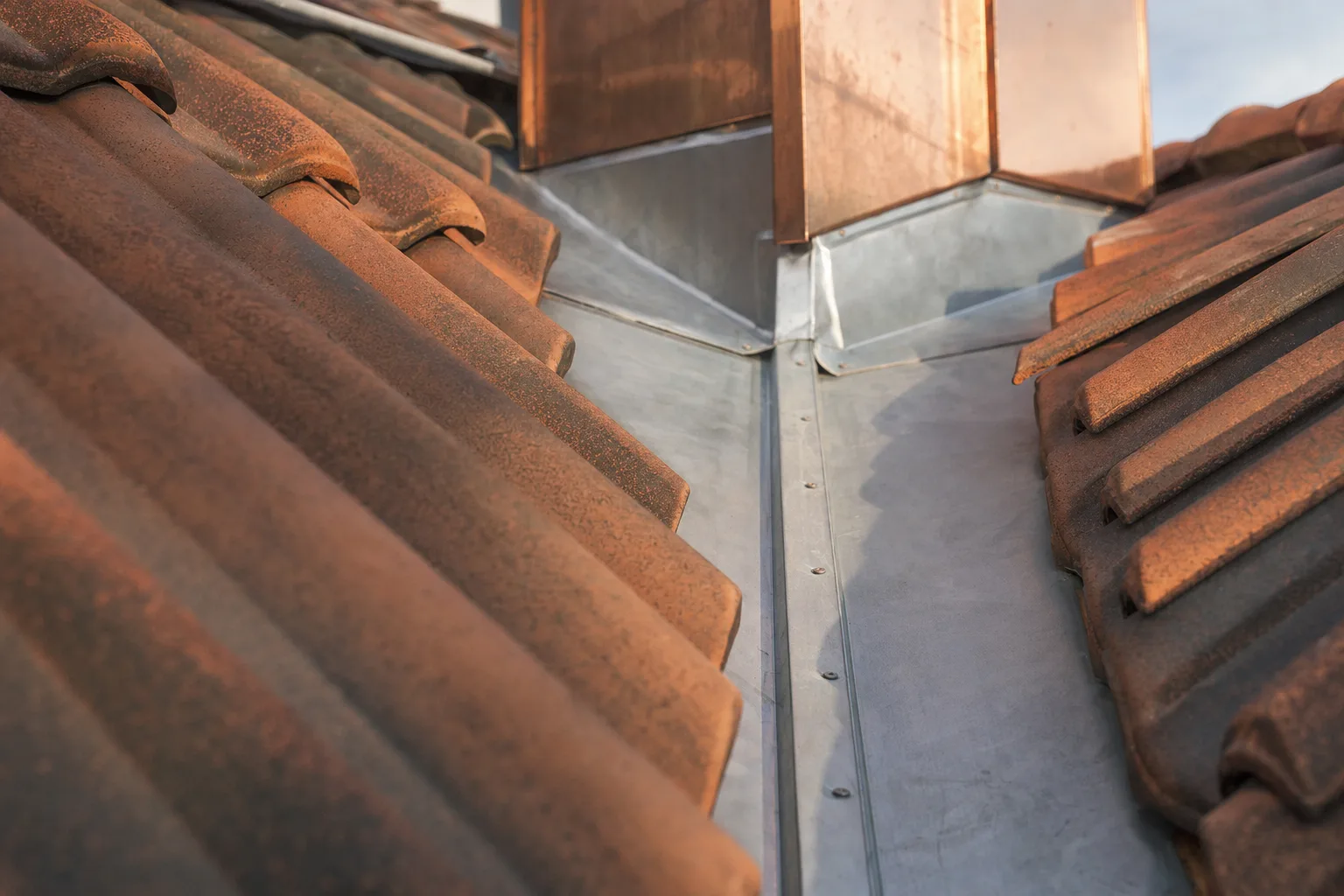 Detailaufnahme einer Zink-Kehle zwischen Ziegeldächern als Symbolbild für den Fachbereich Dachdecker und Spengler.
